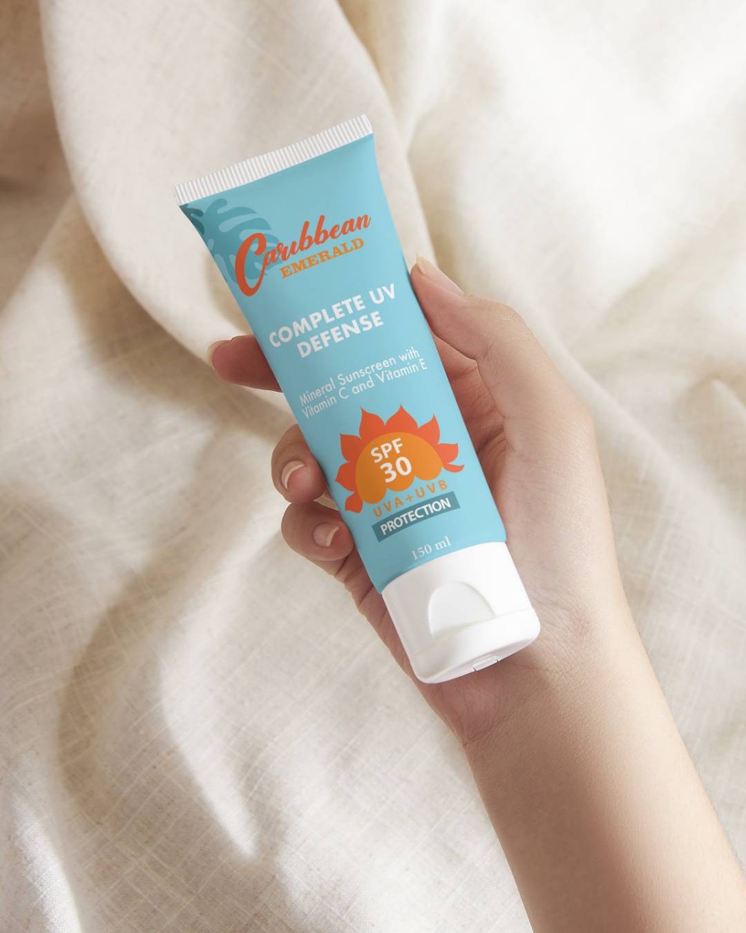 Hand holding a tube of Caribbean Emerald zinc oxide sunscreen with SPF 30 on a beige background
